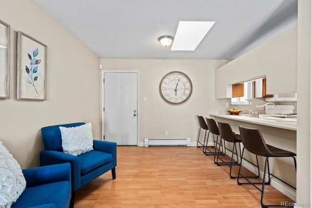 interior space featuring a baseboard radiator, sink, light wood-type flooring, and a skylight