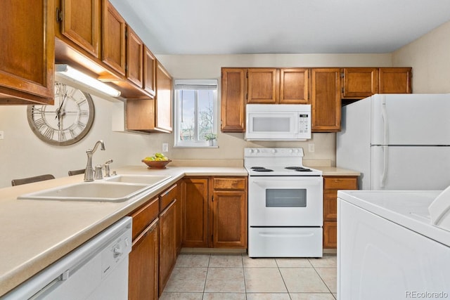 kitchen featuring white appliances, washer / dryer, sink, and light tile patterned floors