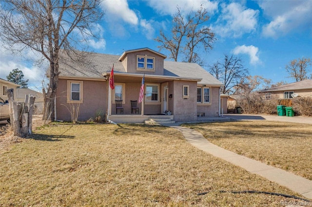 bungalow with stucco siding, covered porch, a front lawn, and fence