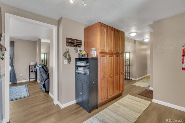 kitchen with a textured ceiling, baseboards, and light wood-style floors