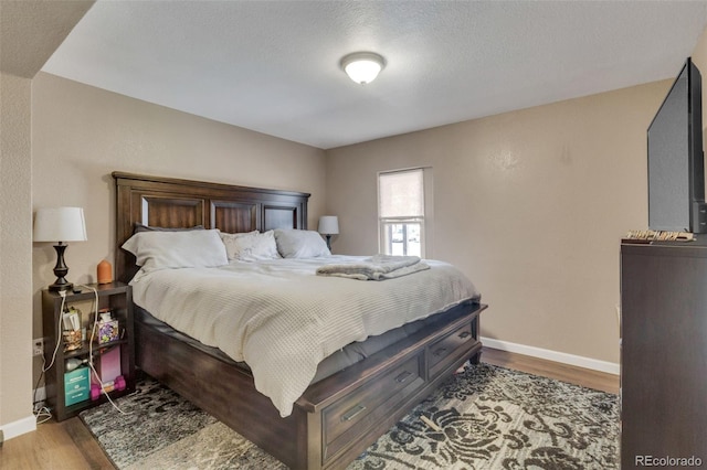 bedroom featuring wood finished floors, baseboards, and a textured ceiling