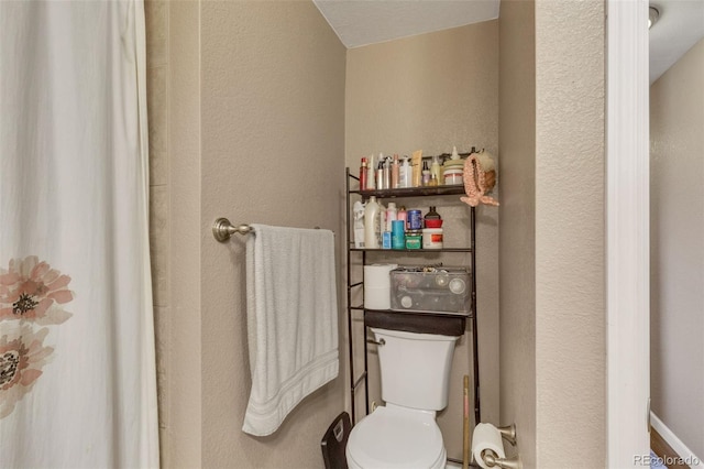 bathroom with toilet and a textured wall