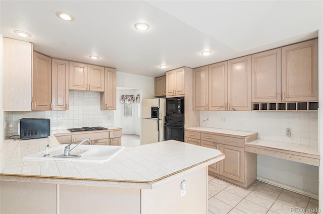 kitchen featuring light brown cabinetry, a sink, tile counters, tasteful backsplash, and black appliances