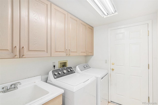 clothes washing area with a sink, cabinet space, and independent washer and dryer