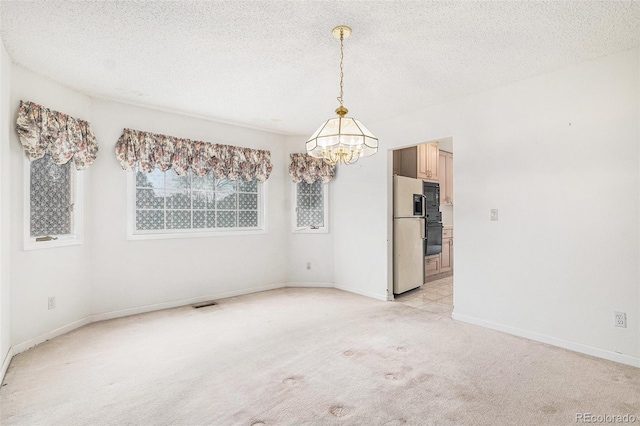 unfurnished room featuring light colored carpet, an inviting chandelier, a textured ceiling, baseboards, and visible vents