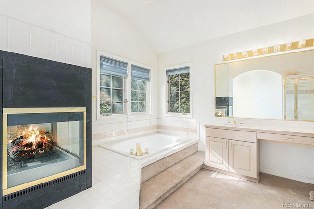 full bath featuring vanity, vaulted ceiling, a bath, and a multi sided fireplace