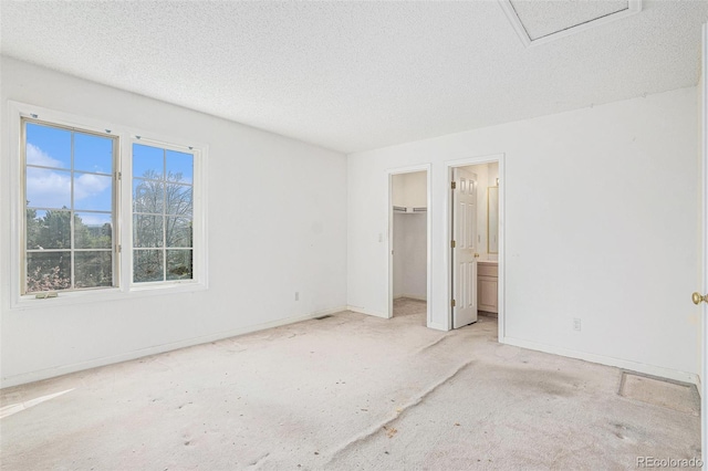 unfurnished bedroom with a closet, baseboards, a textured ceiling, a spacious closet, and carpet