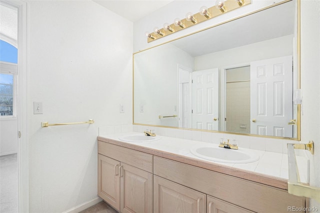 full bathroom with a sink, baseboards, and double vanity