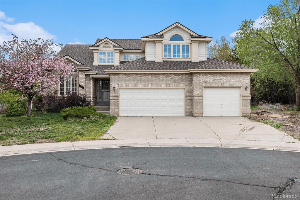 5485 S Jasper Ct, Centennial, CO 80015 - traditional home featuring brick siding, driveway, roof with shingles, and a garage