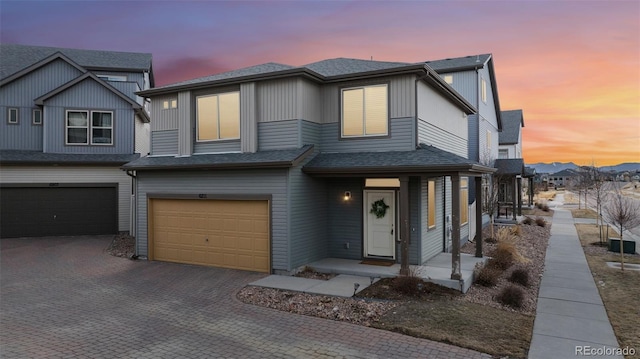 view of front of house featuring a garage, decorative driveway, and roof with shingles