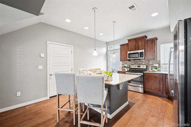 kitchen featuring light wood finished floors, visible vents, appliances with stainless steel finishes, and a center island