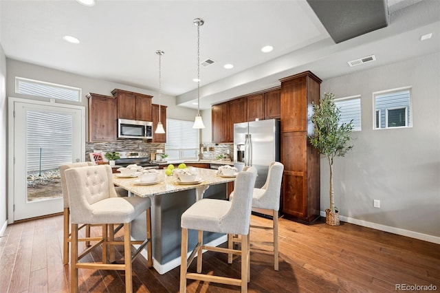 kitchen with tasteful backsplash, visible vents, light wood-style flooring, a kitchen island, and appliances with stainless steel finishes