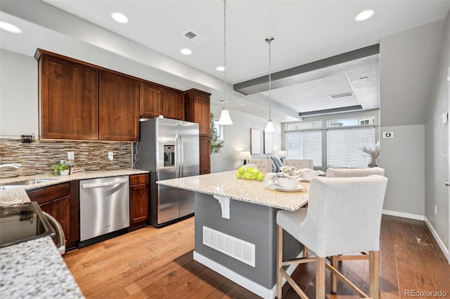 kitchen featuring light wood-type flooring, visible vents, appliances with stainless steel finishes, and decorative backsplash