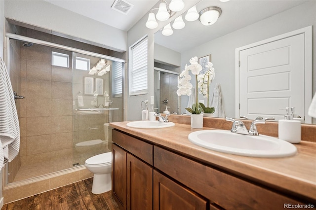 bathroom featuring a stall shower, visible vents, a sink, and wood finished floors