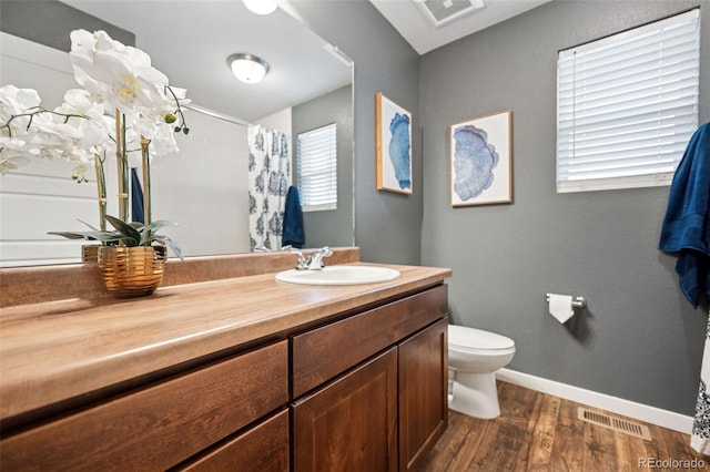 full bathroom with visible vents, a shower with shower curtain, toilet, wood finished floors, and vanity