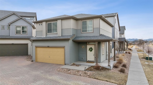 view of front of home featuring a garage, a shingled roof, and decorative driveway