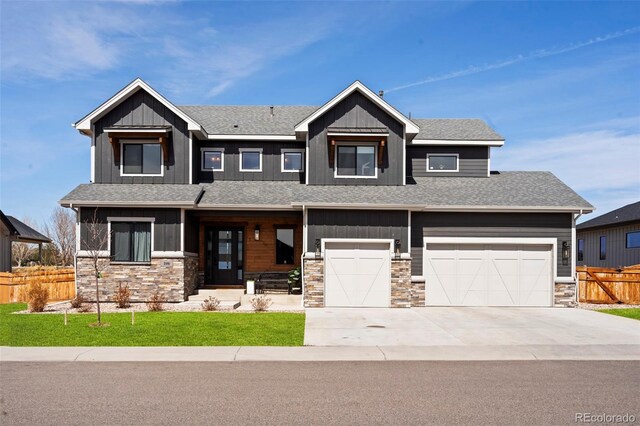 view of front facade featuring board and batten siding, fence, stone siding, and driveway