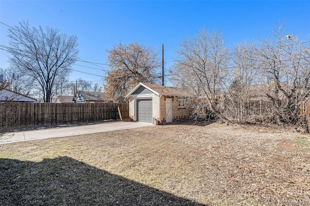 view of yard featuring a garage, an outbuilding, fence, and driveway