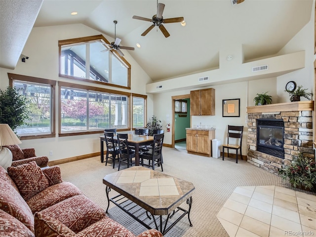 living room featuring a stone fireplace, light carpet, ceiling fan, and high vaulted ceiling