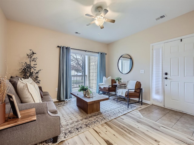 living room with baseboards, ceiling fan, light wood finished floors, and visible vents