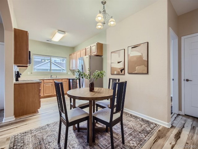 dining area featuring light wood-style floors, baseboards, and a notable chandelier