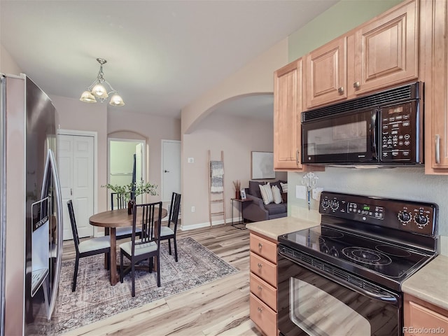 kitchen with light brown cabinets, light wood-style flooring, arched walkways, black appliances, and light countertops