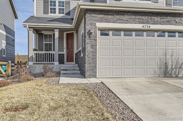 doorway to property with a porch, stone siding, and driveway