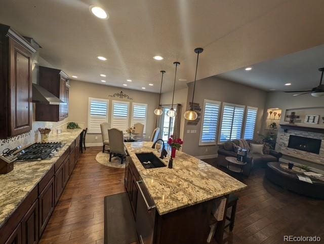 kitchen with dark brown cabinetry, a fireplace, stainless steel appliances, and a sink