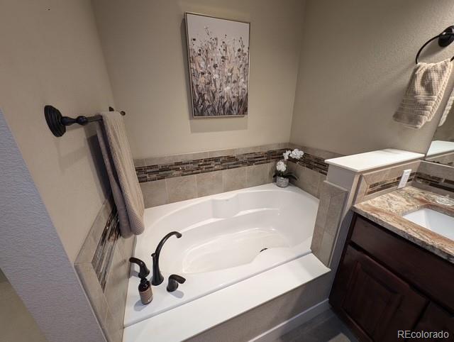 full bath with a garden tub and vanity