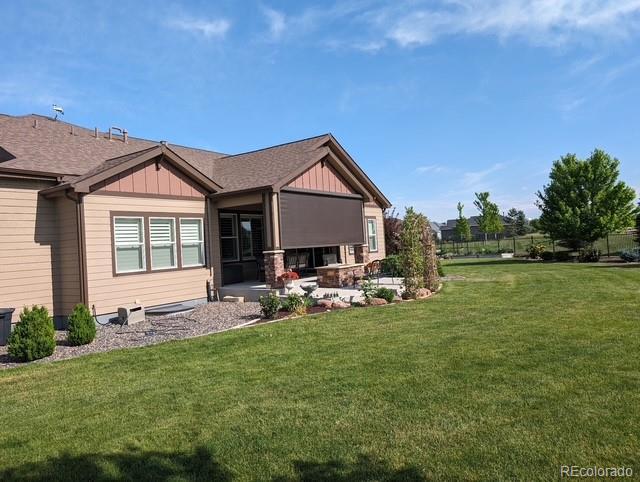 rear view of property with a patio, board and batten siding, and a lawn