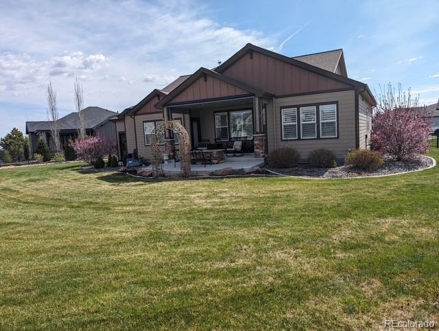 view of front of home featuring board and batten siding, a patio, and a front lawn