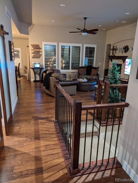 living area with a ceiling fan, recessed lighting, a barn door, and wood finished floors