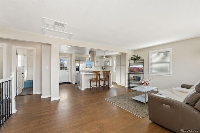 living area featuring dark wood-style flooring, visible vents, and baseboards