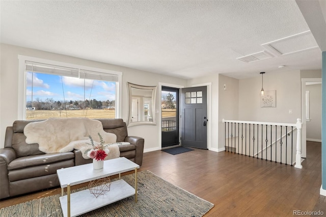 living area featuring baseboards, a textured ceiling, visible vents, and dark wood-type flooring