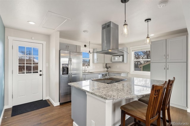 kitchen with white microwave, a sink, light stone countertops, stainless steel fridge, and island exhaust hood