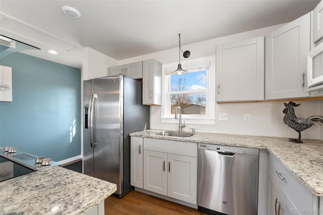 kitchen with recessed lighting, wood finished floors, appliances with stainless steel finishes, a sink, and light stone countertops