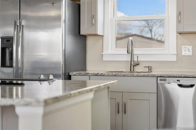 kitchen featuring appliances with stainless steel finishes, a sink, and light stone counters