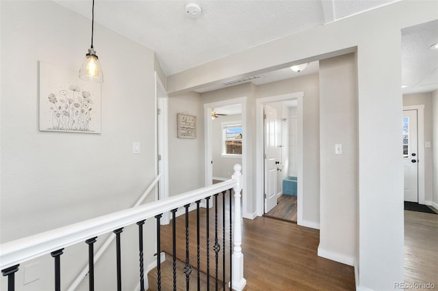 corridor featuring dark wood-style floors, an upstairs landing, and baseboards