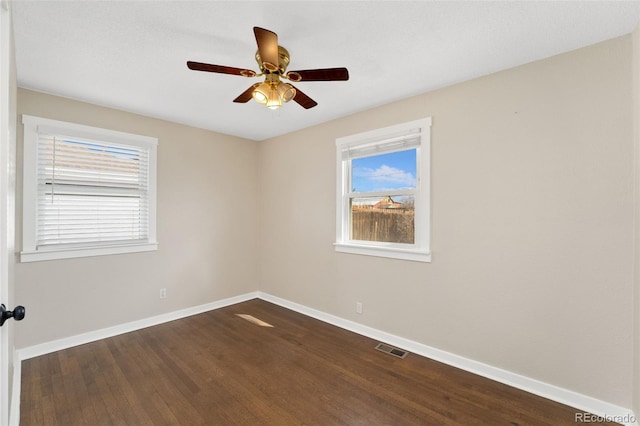 unfurnished room with dark wood-type flooring, a ceiling fan, visible vents, and baseboards