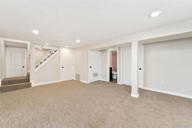 finished below grade area featuring carpet, visible vents, stairway, and baseboards