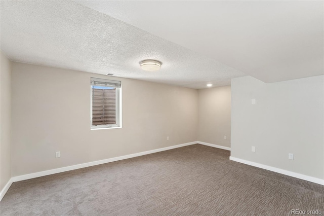 carpeted spare room featuring a textured ceiling and baseboards