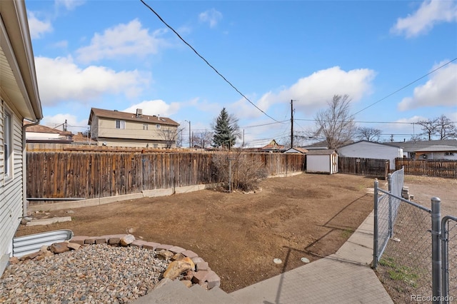 view of yard featuring a storage shed, a fenced backyard, and an outbuilding