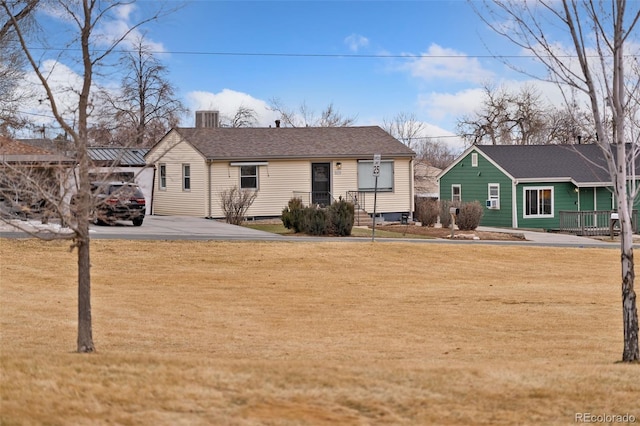 view of front of property with roof with shingles, a front lawn, and a chimney