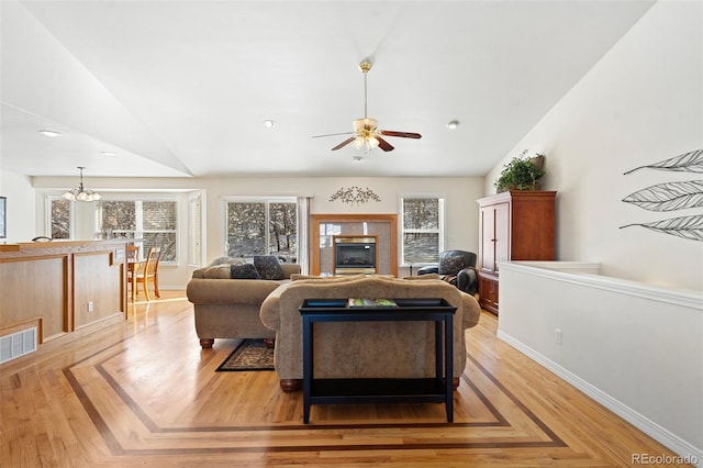 living room with ceiling fan with notable chandelier and lofted ceiling