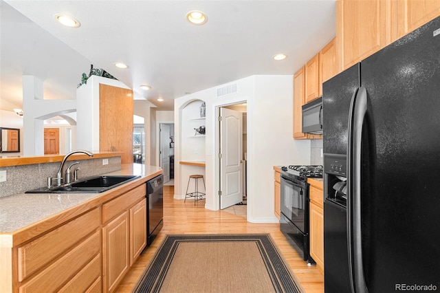 kitchen featuring sink, light hardwood / wood-style floors, black appliances, and light brown cabinets