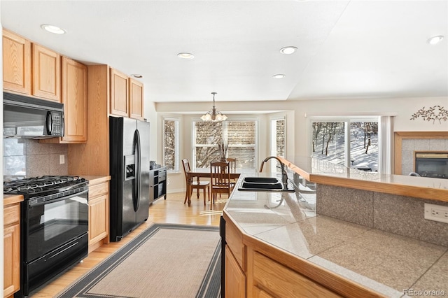 kitchen with sink, an inviting chandelier, pendant lighting, a wealth of natural light, and black appliances