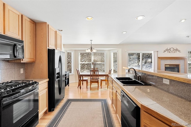 kitchen with sink, decorative light fixtures, an inviting chandelier, backsplash, and black appliances