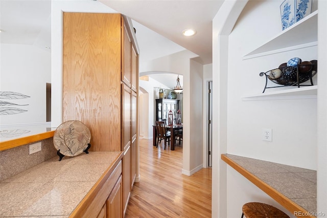 hallway with light hardwood / wood-style floors and vaulted ceiling