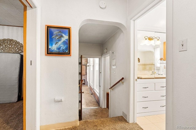 hallway with sink and light colored carpet