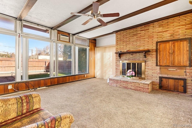 unfurnished living room with beamed ceiling, plenty of natural light, carpet floors, and a brick fireplace